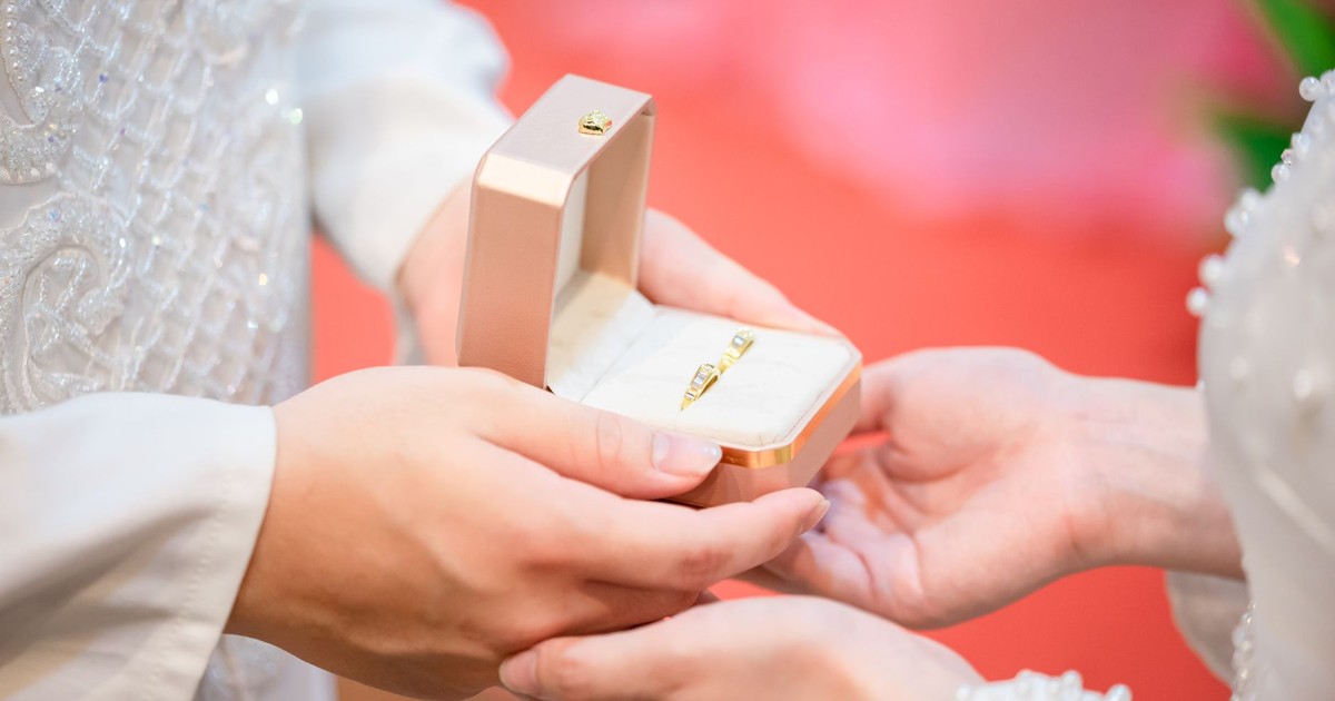 Close-up of hands exchanging wedding rings during a ceremony.