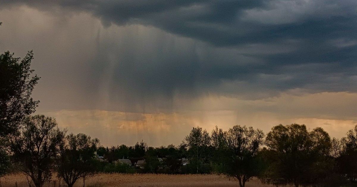 Dark storm clouds gather over a rural field, hinting at approaching rain. Captured in detail, this scene evokes a sense of impending weather change.