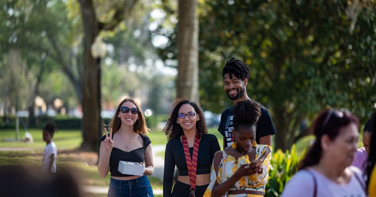 Group of friends smiling and enjoying a sunny day outdoors in the park.