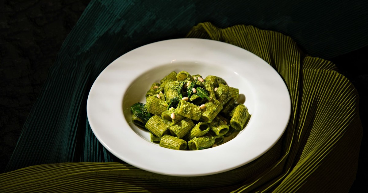 A plate of delicious rigatoni pasta with fresh spinach pesto arranged artfully.