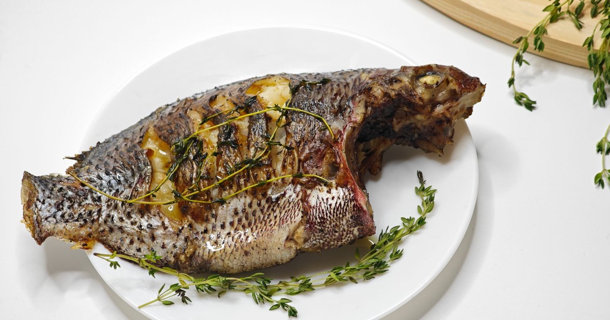 Grilled whole fish garnished with fresh thyme on a white platter.