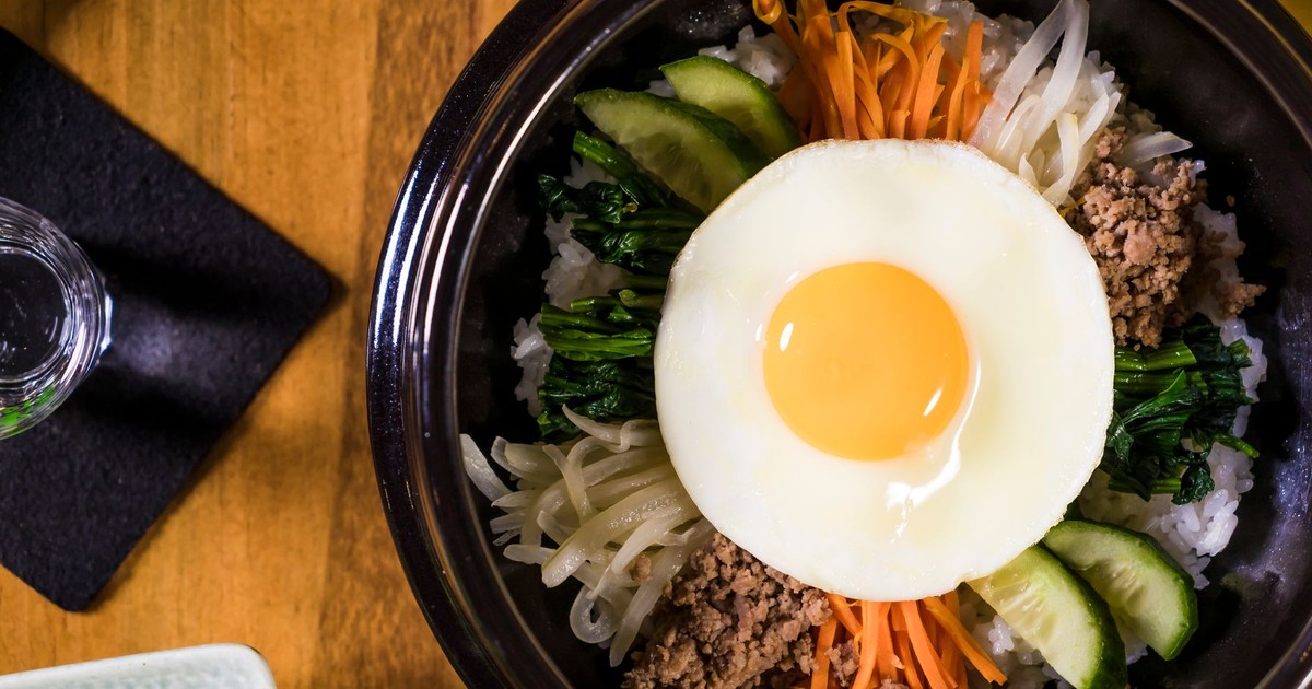 Delicious Korean Bibimbap dish featuring a fried egg, fresh vegetables, and savory beef, perfect for lunch or dinner.
