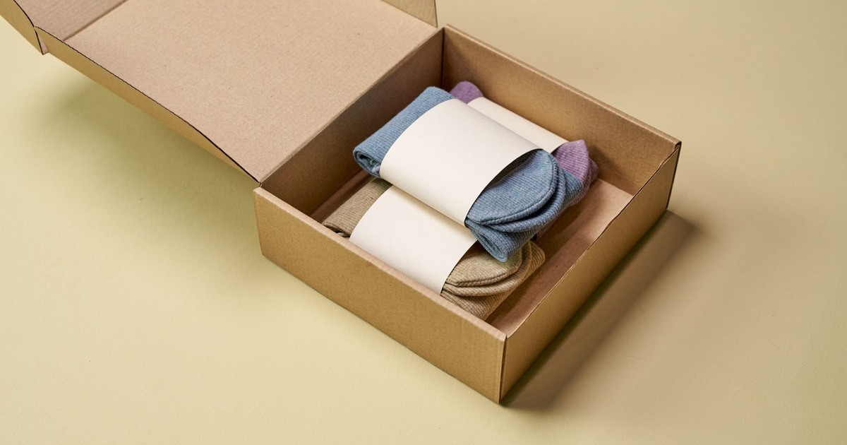 Multicolored socks neatly arranged inside open cardboard packaging on a neutral background.