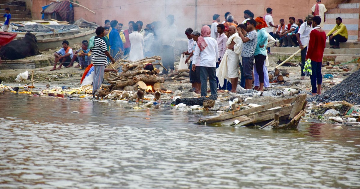 A gathering of people by the sacred Ganges River in Varanasi, engaged in a traditional ceremony.