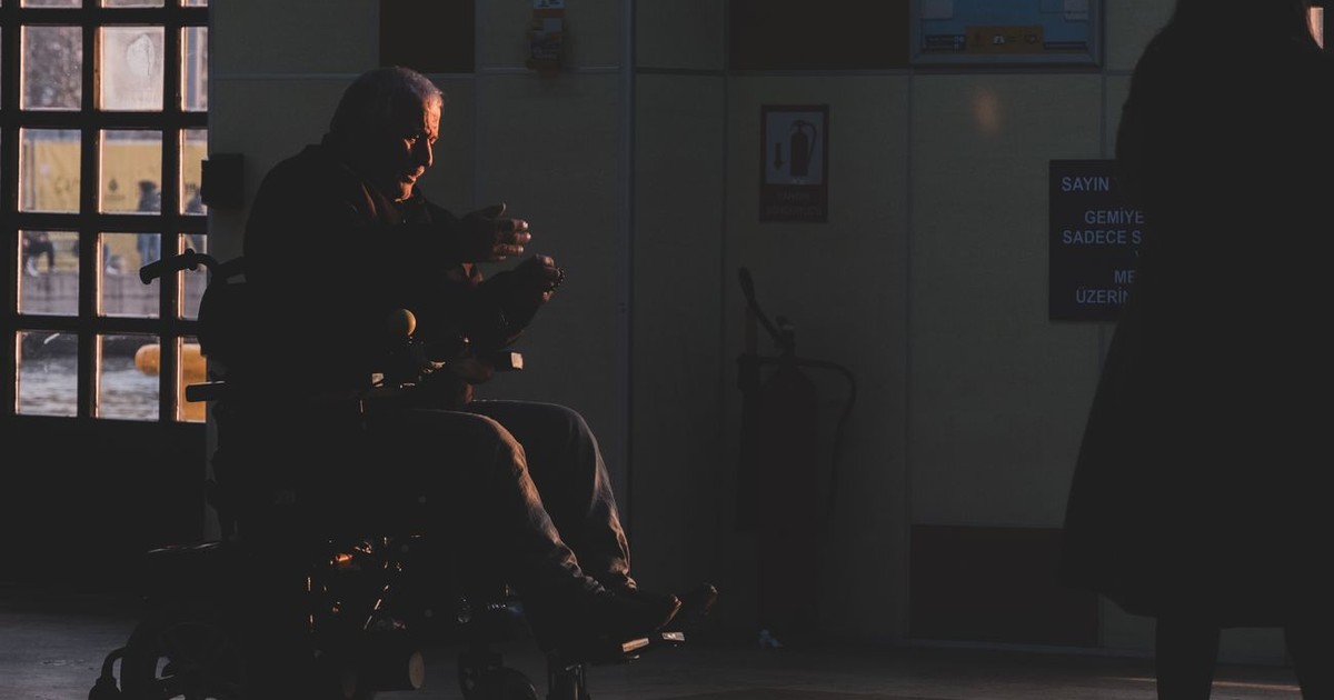 Silhouette of a person in a wheelchair inside a hospital corridor during sunset.