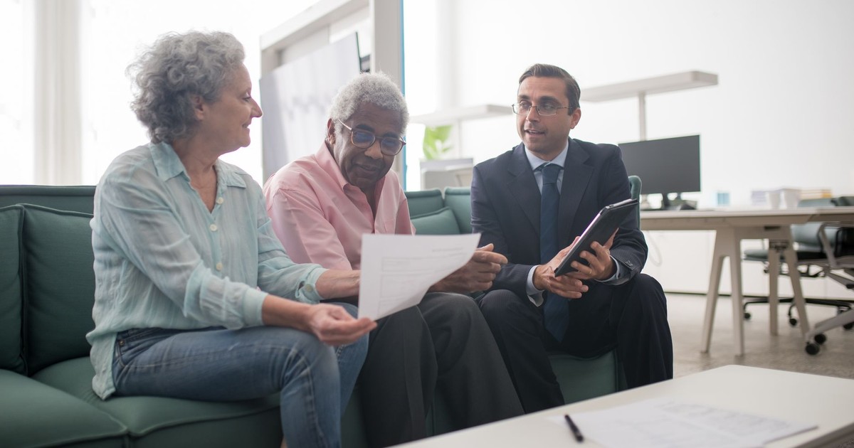 Senior couple discussing documents with a business advisor in a modern office setting.