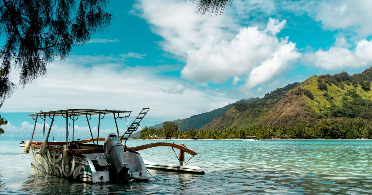A picturesque scene of a boat resting in the calm waters of Moorea, French Polynesia, under a bright blue sky.