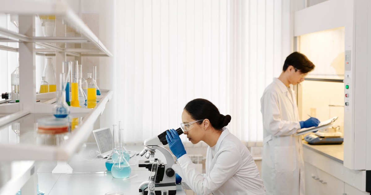 Two scientists working in a well-equipped laboratory with microscopes and test tubes.