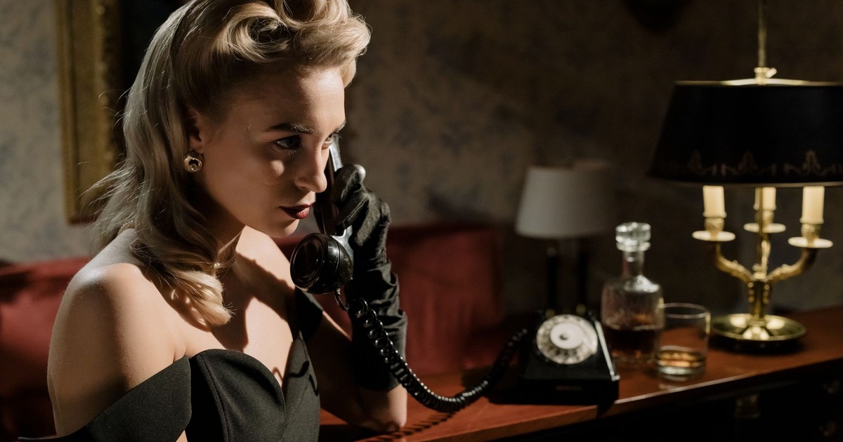 Stylish 1950s woman in a dark room, elegantly on the phone.