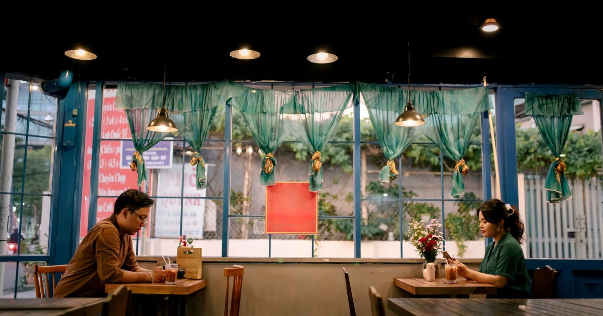 Two adults enjoying a relaxed meeting in a cozy cafe with vintage decor and soft lighting.