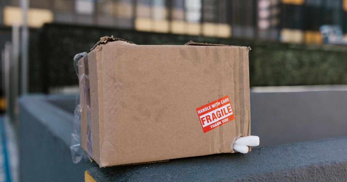 Close-up of a fragile cardboard box on a concrete ledge in an urban setting, symbolizing delivery challenges.