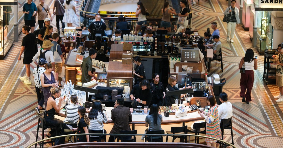A bustling coffee shop inside a high-end shopping mall filled with diverse visitors and elegant decor.