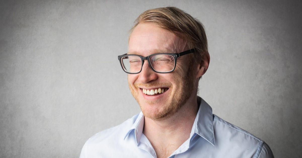 Studio portrait of a smiling man wearing eyeglasses, exuding joy and happiness.