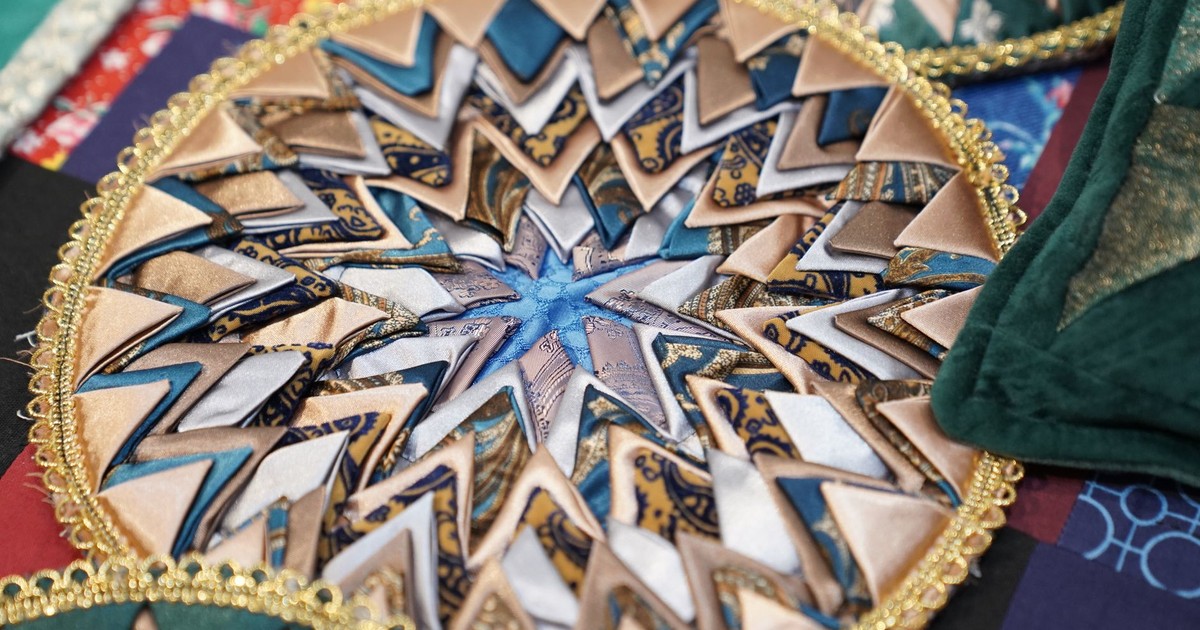 Closeup of a colorful, intricate quilted mandala pattern showcasing geometric designs and fabric textures.