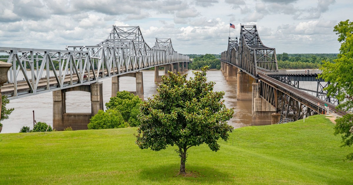 View of the Vicksburg Bridge spanning the Mississippi River under cloudy sky.