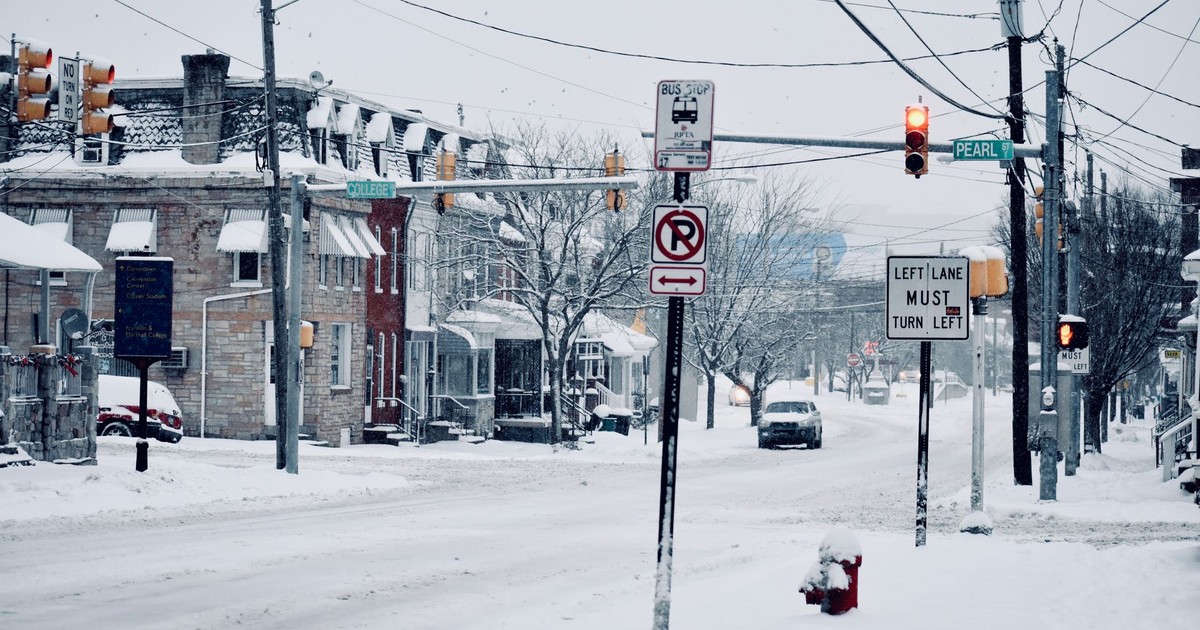 A winter street view in Lancaster, PA showcasing snowy roads, traffic signs, and parked vehicles.