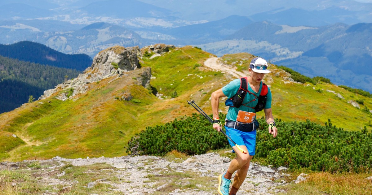 Athletic man trail running on a scenic mountain trail during the day.