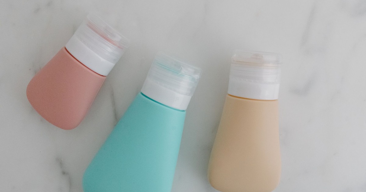 Three colorful squeezable bottles with flip tops on a marble surface.