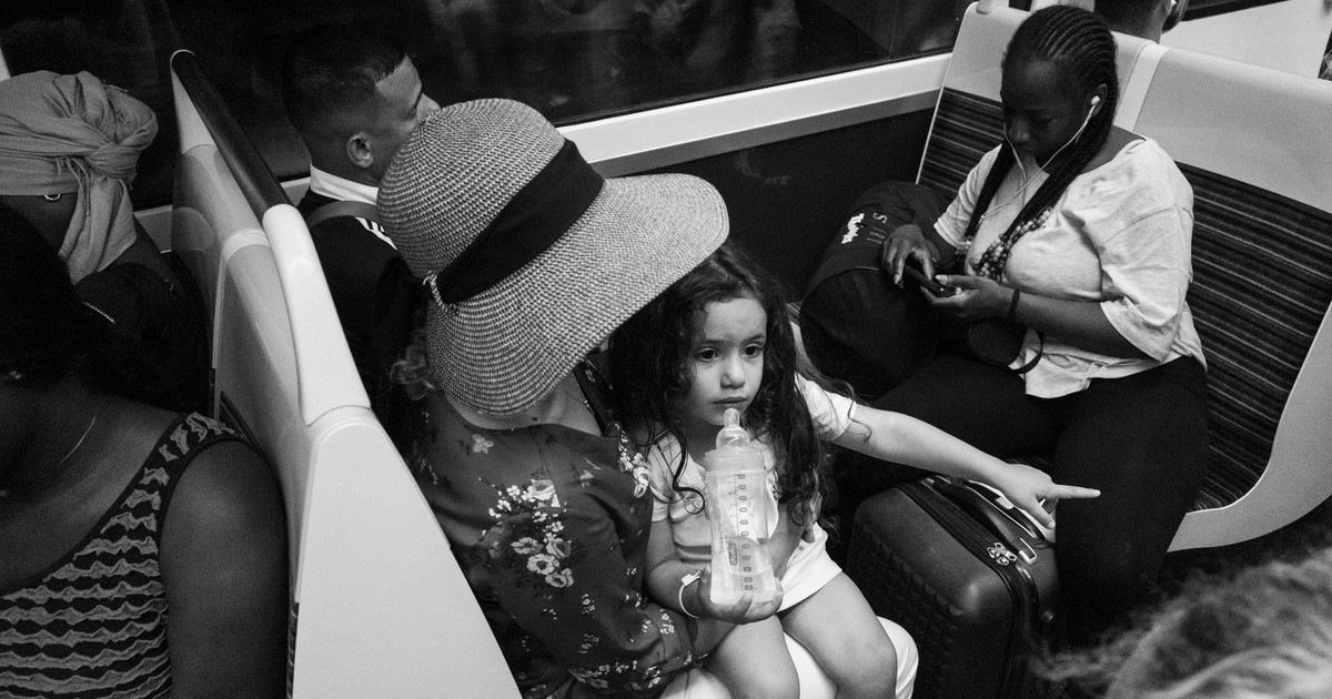 A mother and daughter share a moment during a subway journey, capturing urban life.