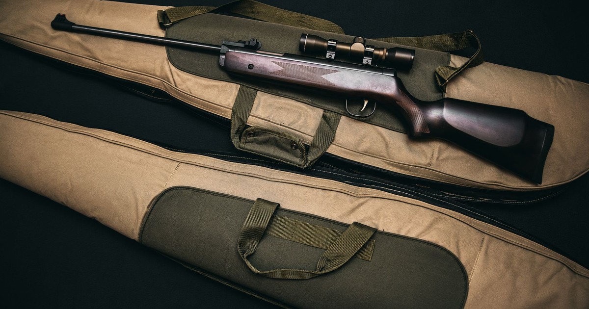 Close-up of a hunting rifle with a scope on a carrying bag, showcasing firearms and hunting gear.