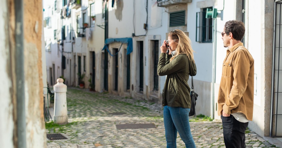 A couple exploring a quaint, cobblestone street and capturing the moment on camera. Perfect for travel themes.
