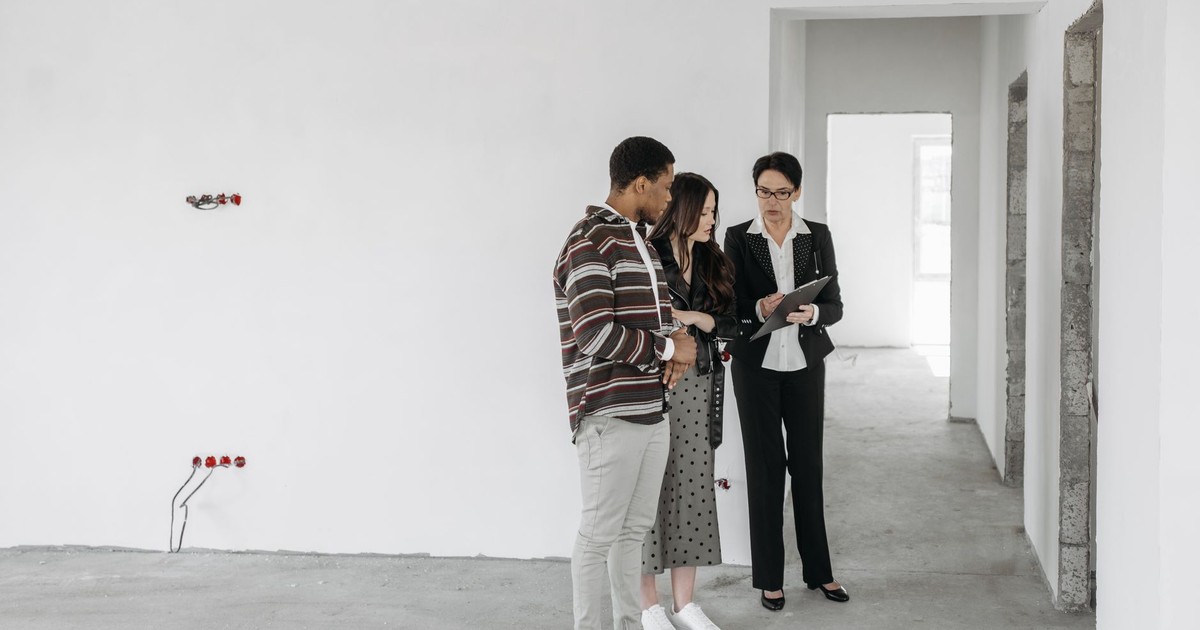 A couple and realtor discuss details in an unfinished property. Ideal for real estate themes.