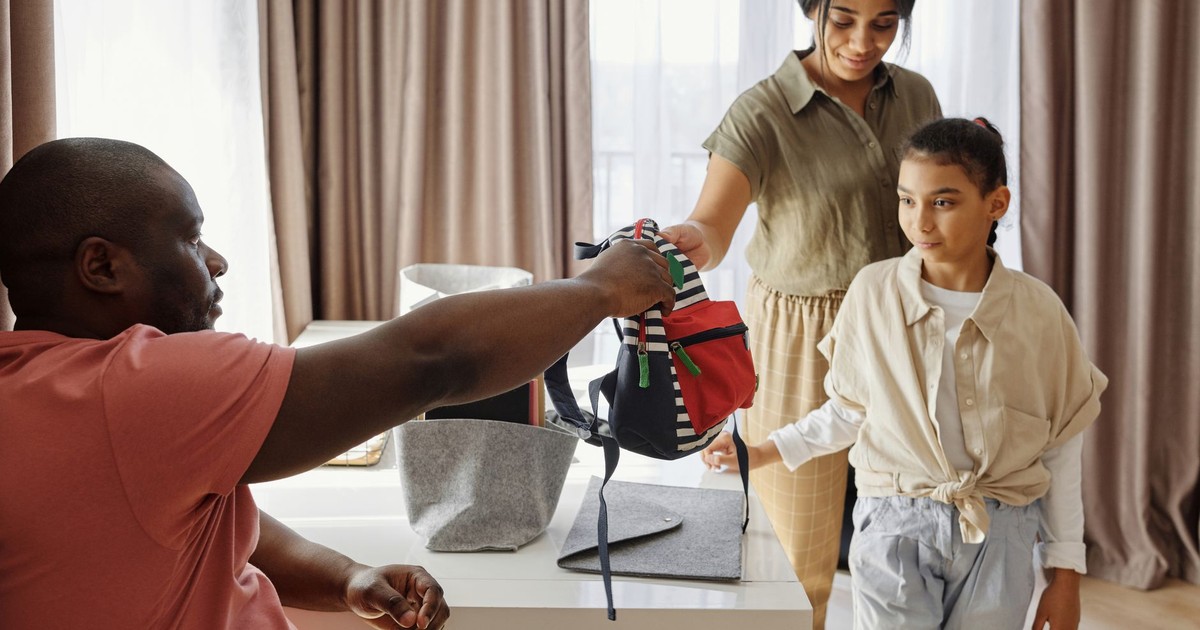 Family helping child get ready for school in a cozy indoor setting.