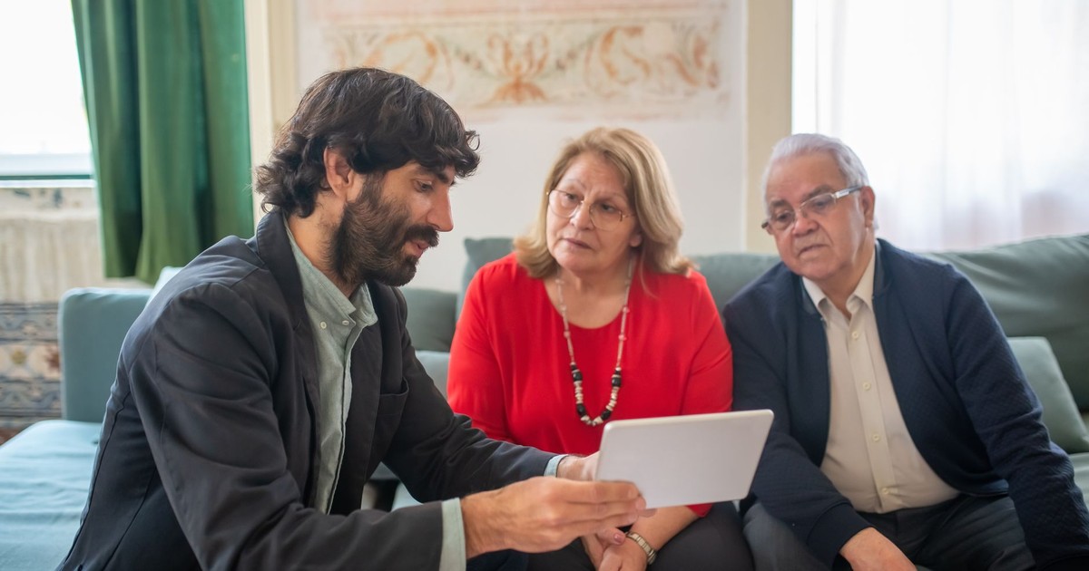 A financial advisor discussing investment options with an elderly couple in a cozy living room.