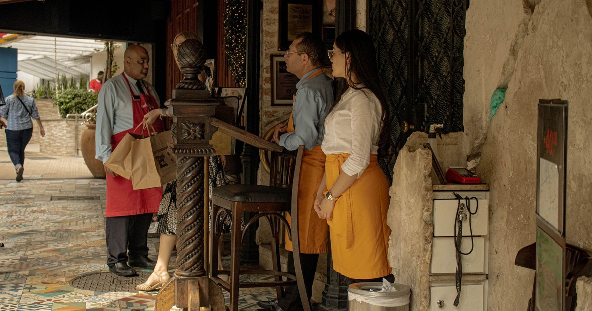Restaurant staff interacting with customers at entrance, providing a welcoming atmosphere.