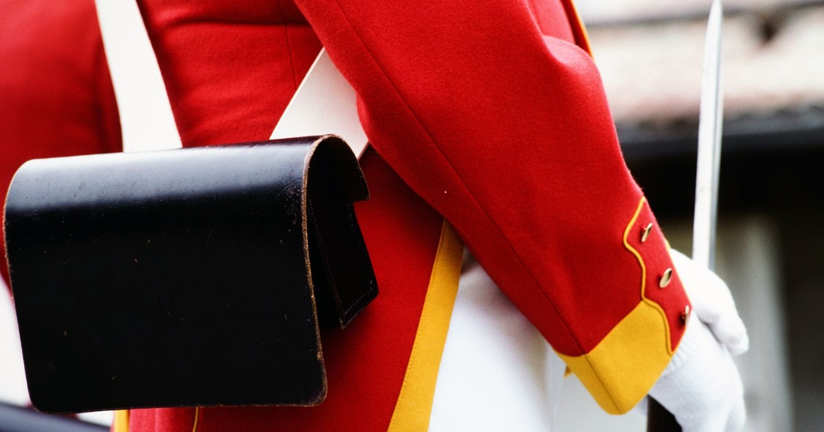 Detail view of a red historical military uniform with a black leather pouch and white glove.