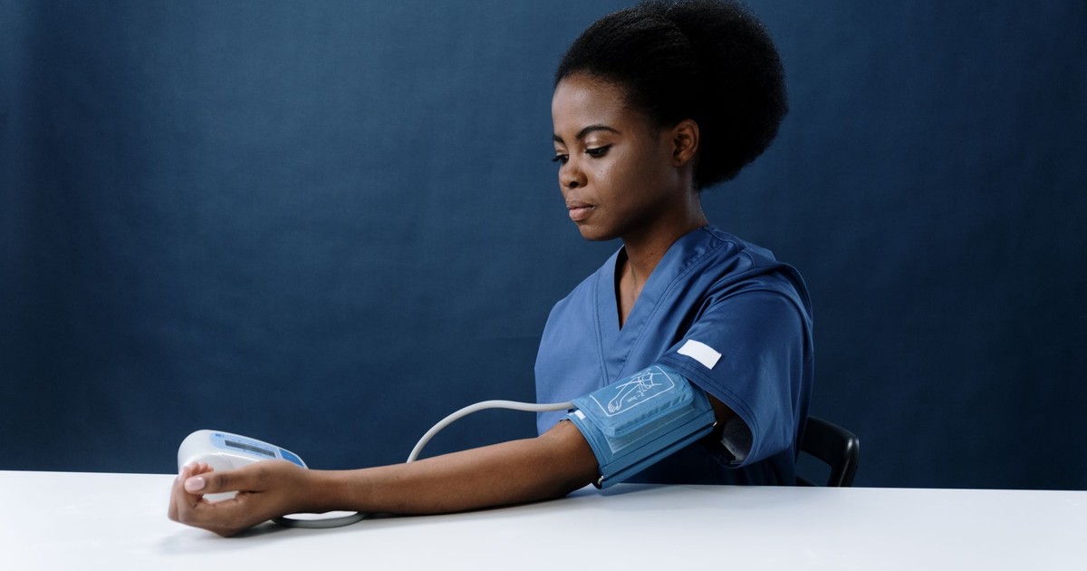 African American nurse measuring blood pressure, representing healthcare and medical practice.