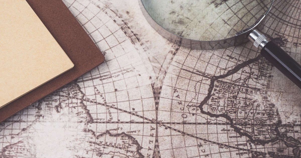 A close-up of a vintage map, magnifying glass, and notebook, perfect for research themes.