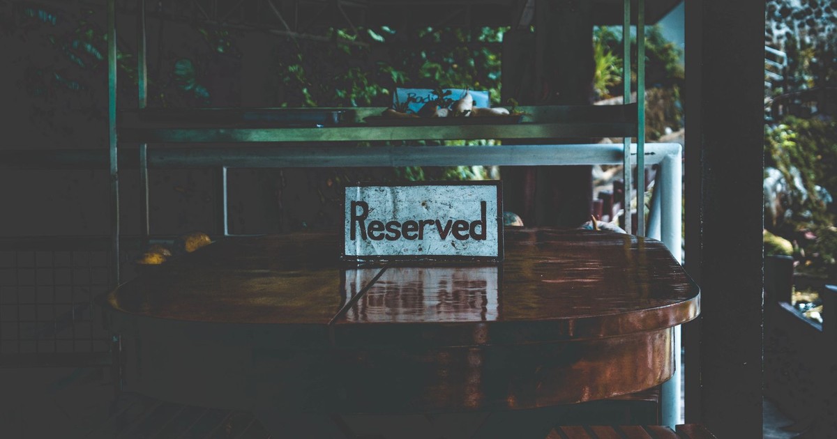 A dimly lit table with a reserved sign, set in an outdoor environment creating a moody atmosphere.