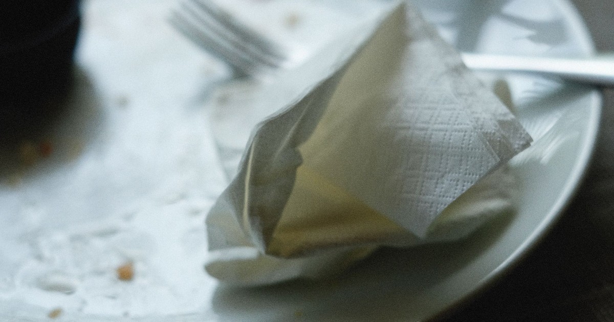 A close-up of an empty plate with a crumpled napkin and fork, creating a post-meal scene.