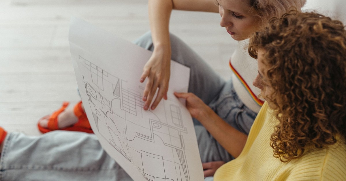 Two women discussing and planning with a floor plan indoors.