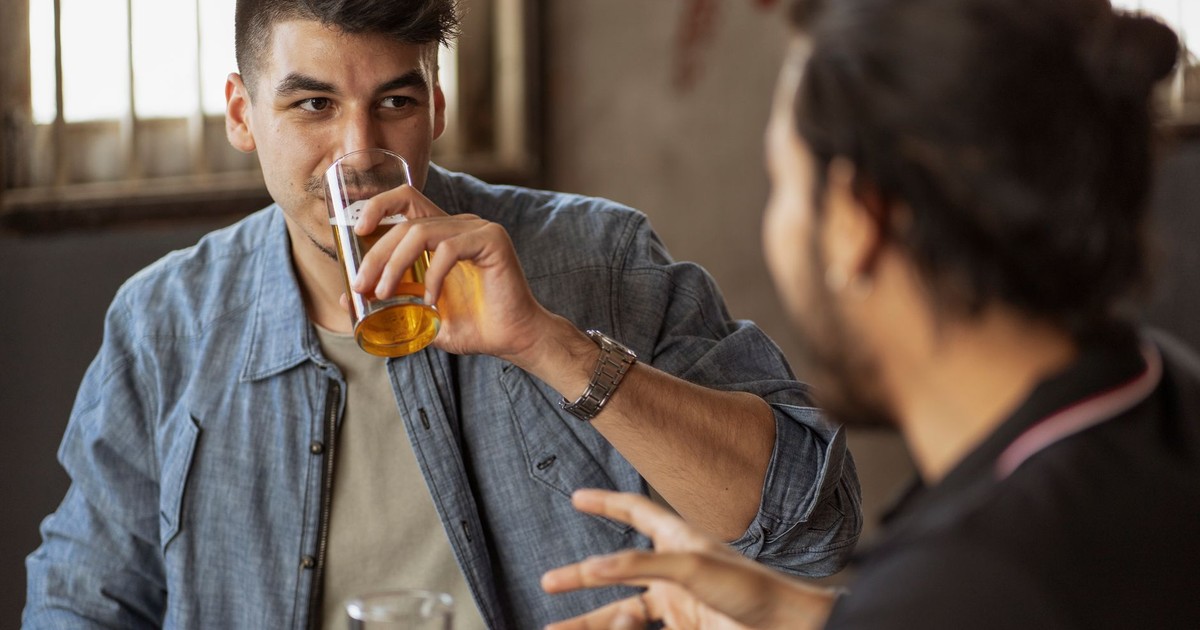 Two friends enjoying a casual conversation over drinks indoors. Perfect for lifestyle and social themes.