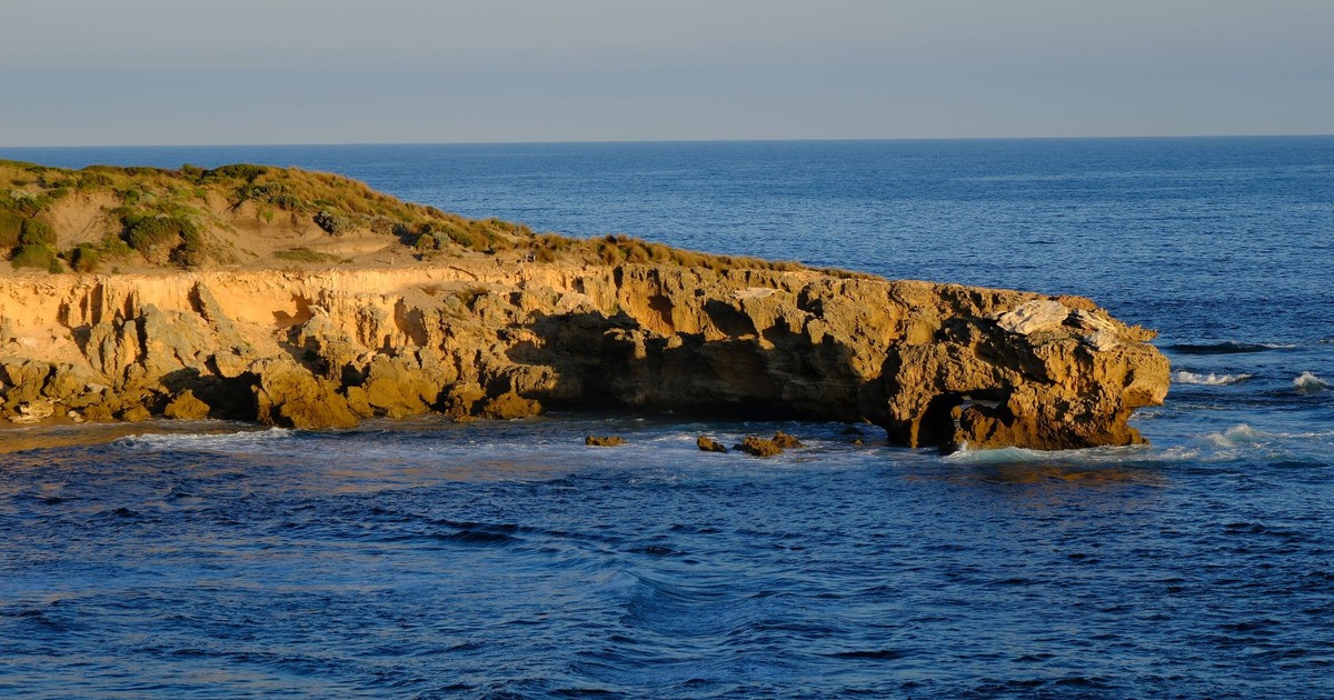 A beautiful coastal cliff reflecting on the ocean at sunset, capturing nature's serenity.