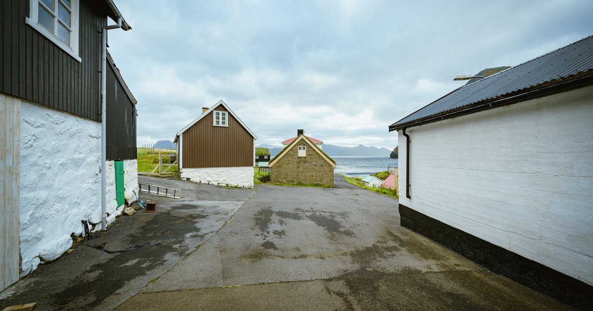 Charming coastal village street perspective with traditional houses and distant sea view.