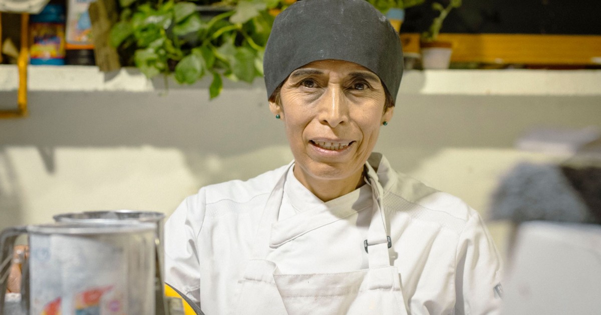 Portrait of a female chef in a Mexico City kitchen wearing apron and hat.