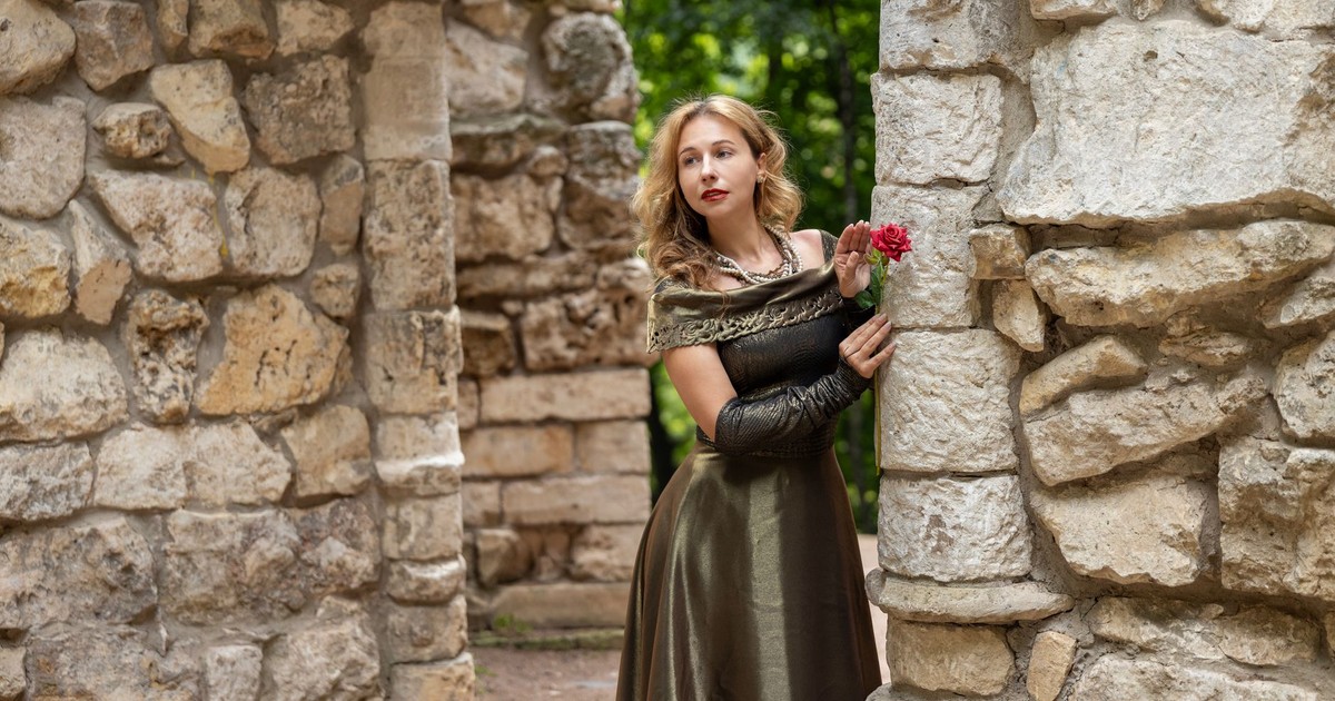 Woman in medieval dress with a rose amidst stone ruins, exuding timeless beauty.