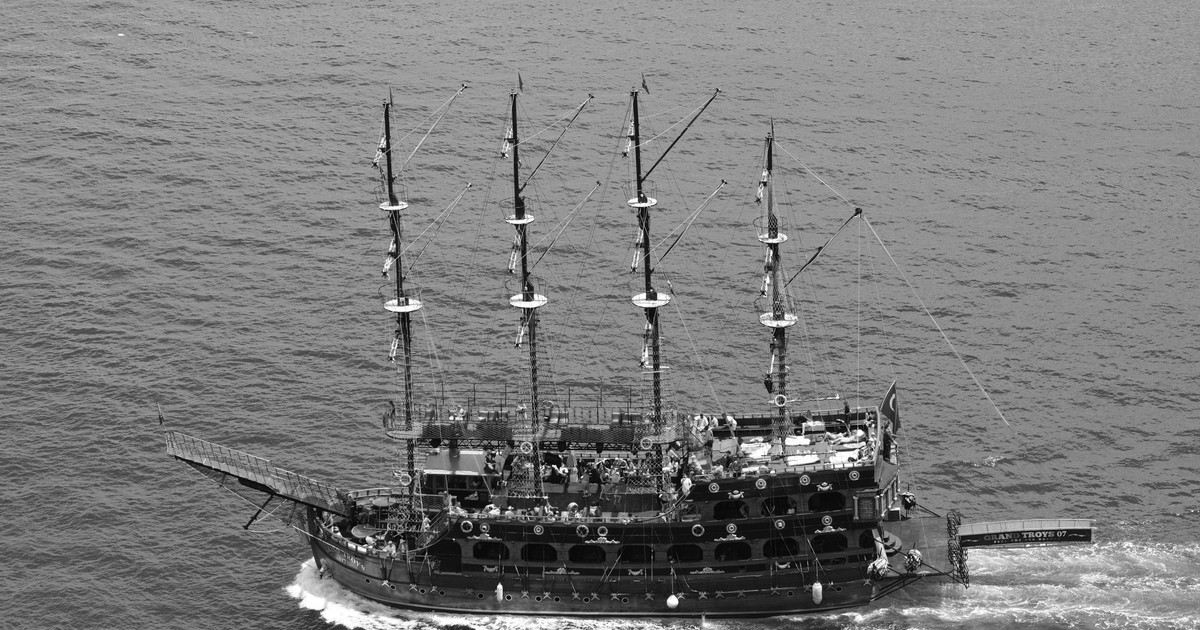 Aerial black and white photo of a pirate ship sailing the ocean, showcasing nautical adventure.