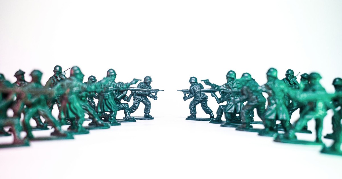 Green toy soldiers facing off on a white background, symbolic of conflict and strategy.