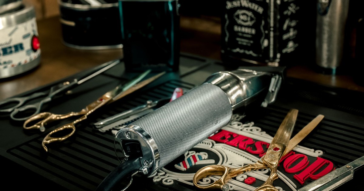 Close-up of barber tools including electric razor and scissors on a salon counter.