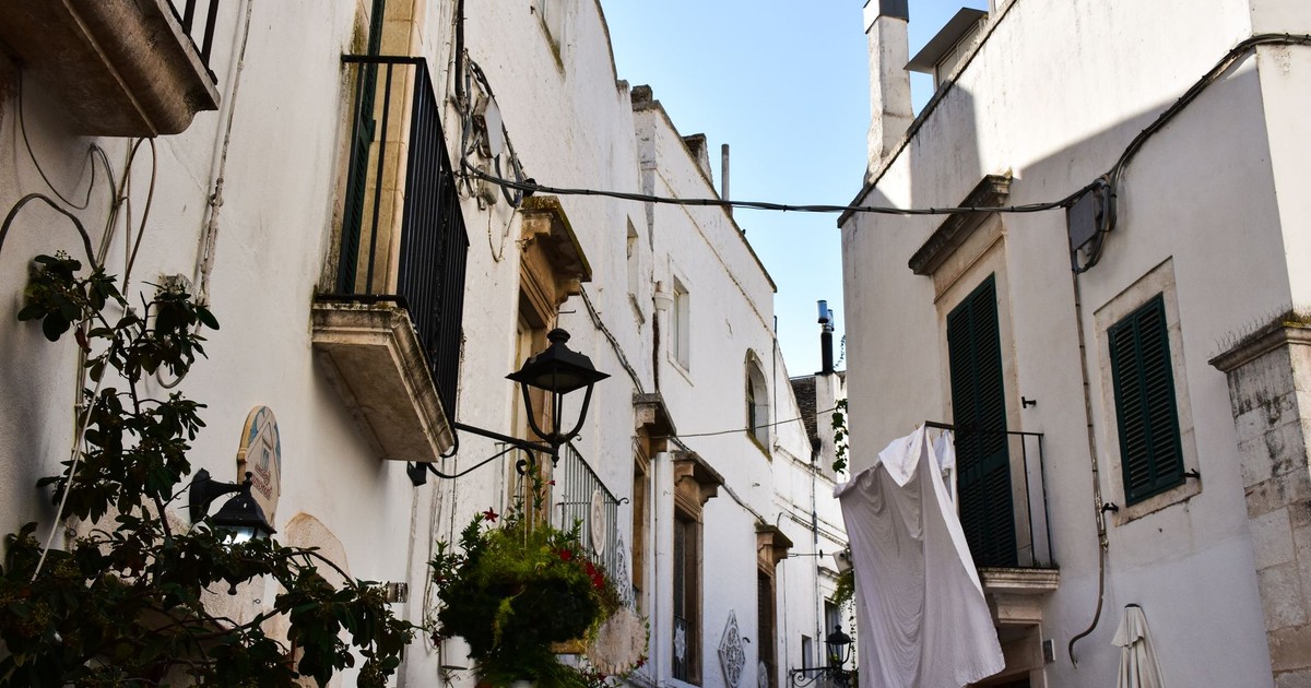 Picturesque narrow alley in Puglia with whitewashed buildings and vibrant flowers.