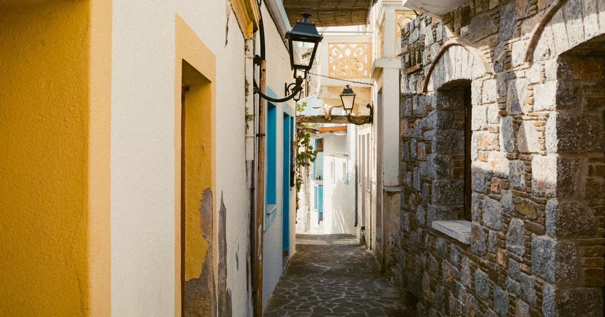 Scenic narrow alley with stone buildings and vibrant colors in Olympos, Greece.