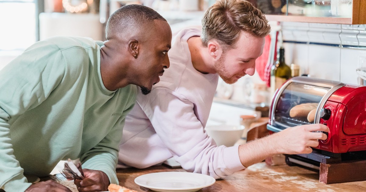 Two men making breakfast with a toaster in a cozy kitchen setting.