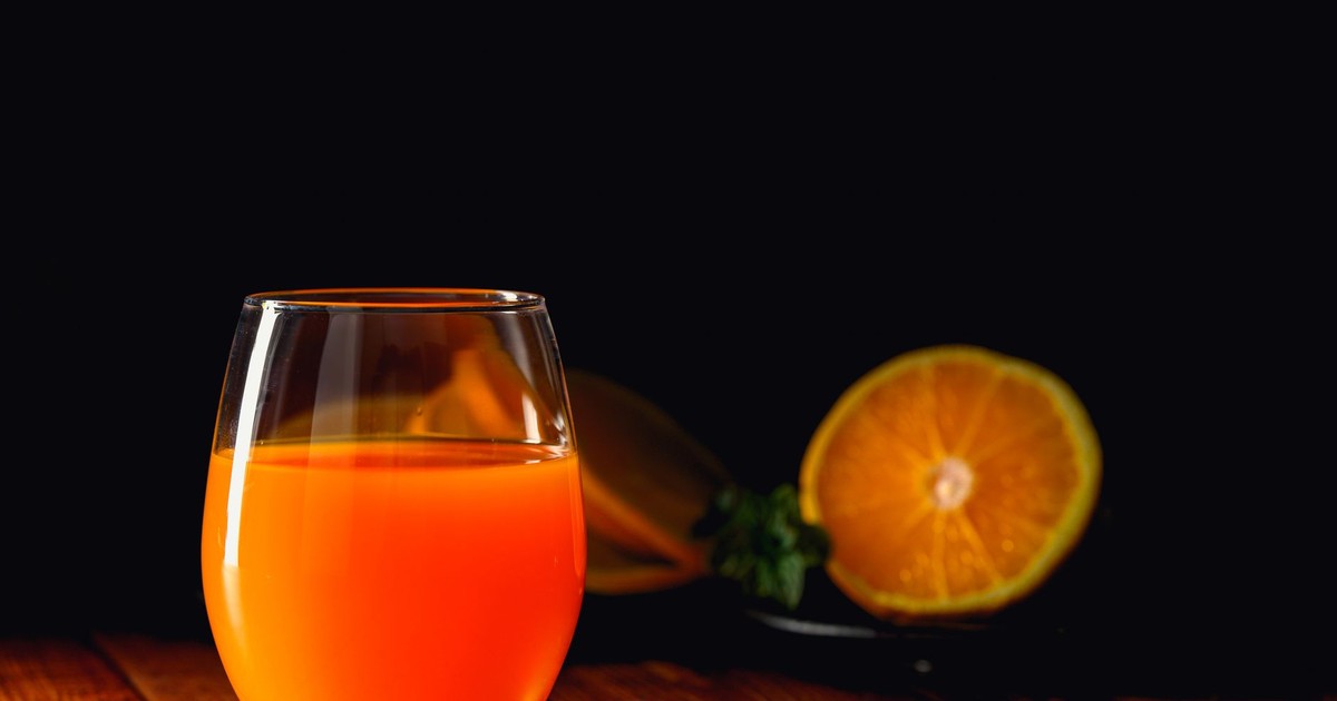 A refreshing glass of bright orange juice on a wood surface, perfect for a healthy start.