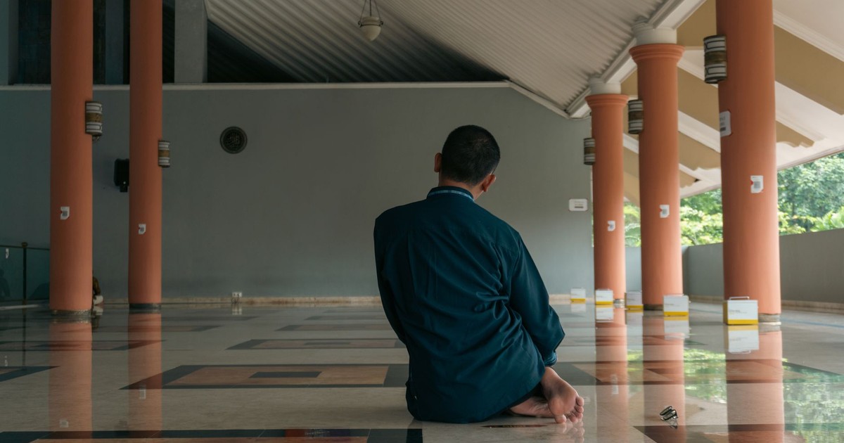 A man sitting and praying inside a mosque in Yogyakarta, Indonesia, reflecting devotion.