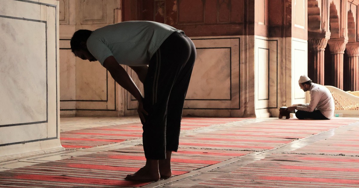 Two men praying inside the historic Jama Masjid in Delhi, India, highlighting spirituality and tradition.
