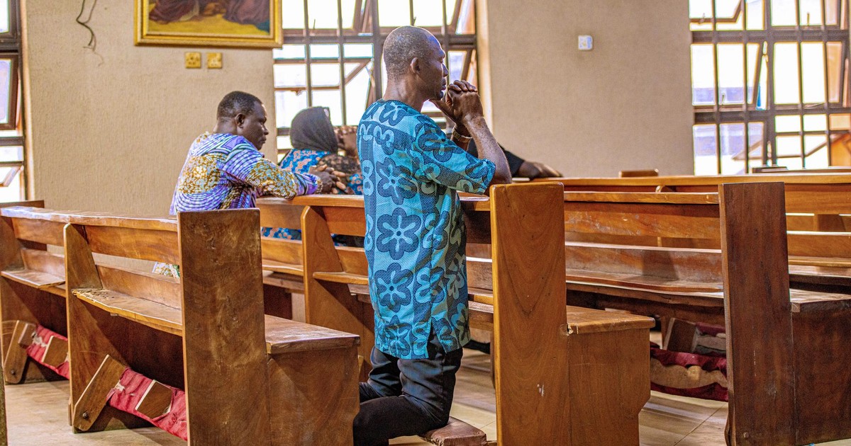 Adults kneeling and praying in a church in Benin City, Nigeria, depicting spirituality and devotion.